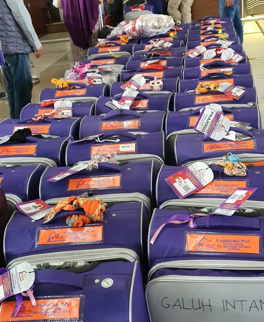 Tas perlengkapan jamaah berwarna ungu tertata di setiap kursi kabin pesawat