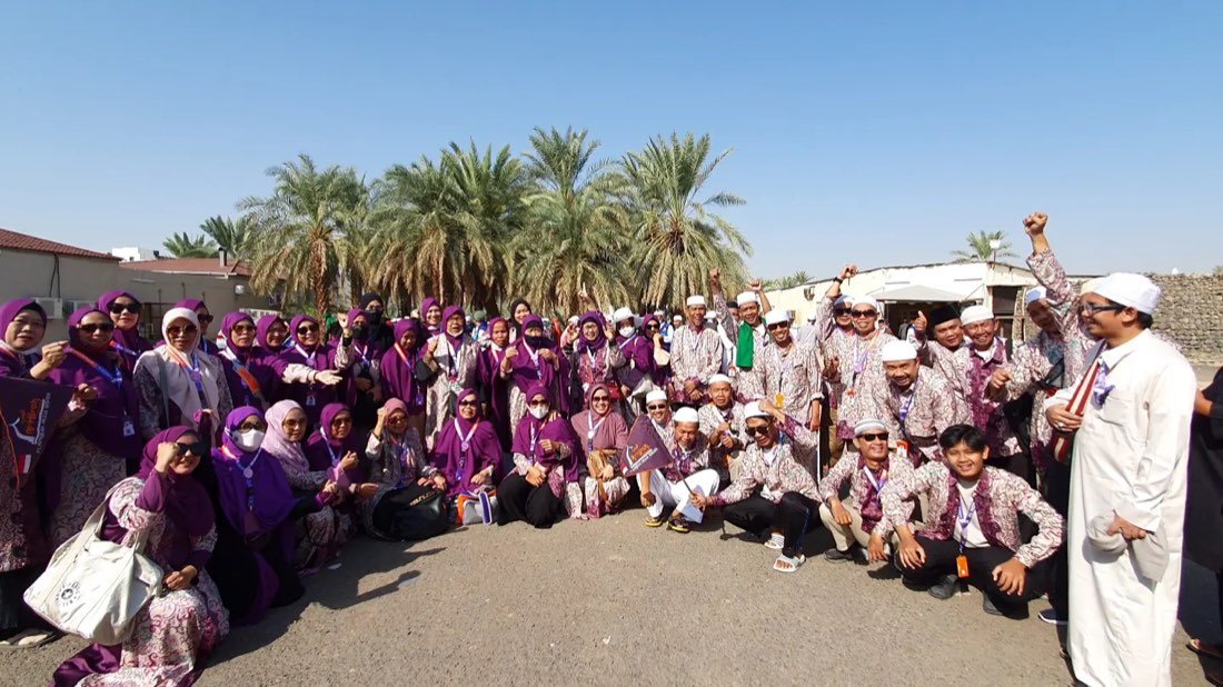 Rombongan jamaah duduk berkumpul di antara pohon kurma di kebun kurma Madinah