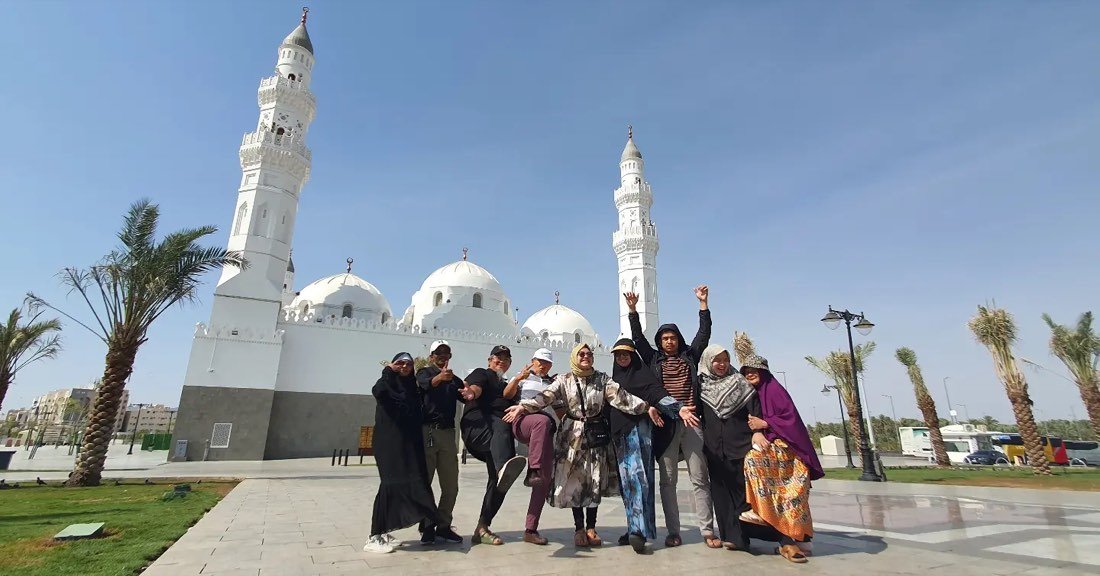 Rombongan jamaah berfoto dengan tangan terangkat di depan kubah putih Masjid Quba, Madinah
